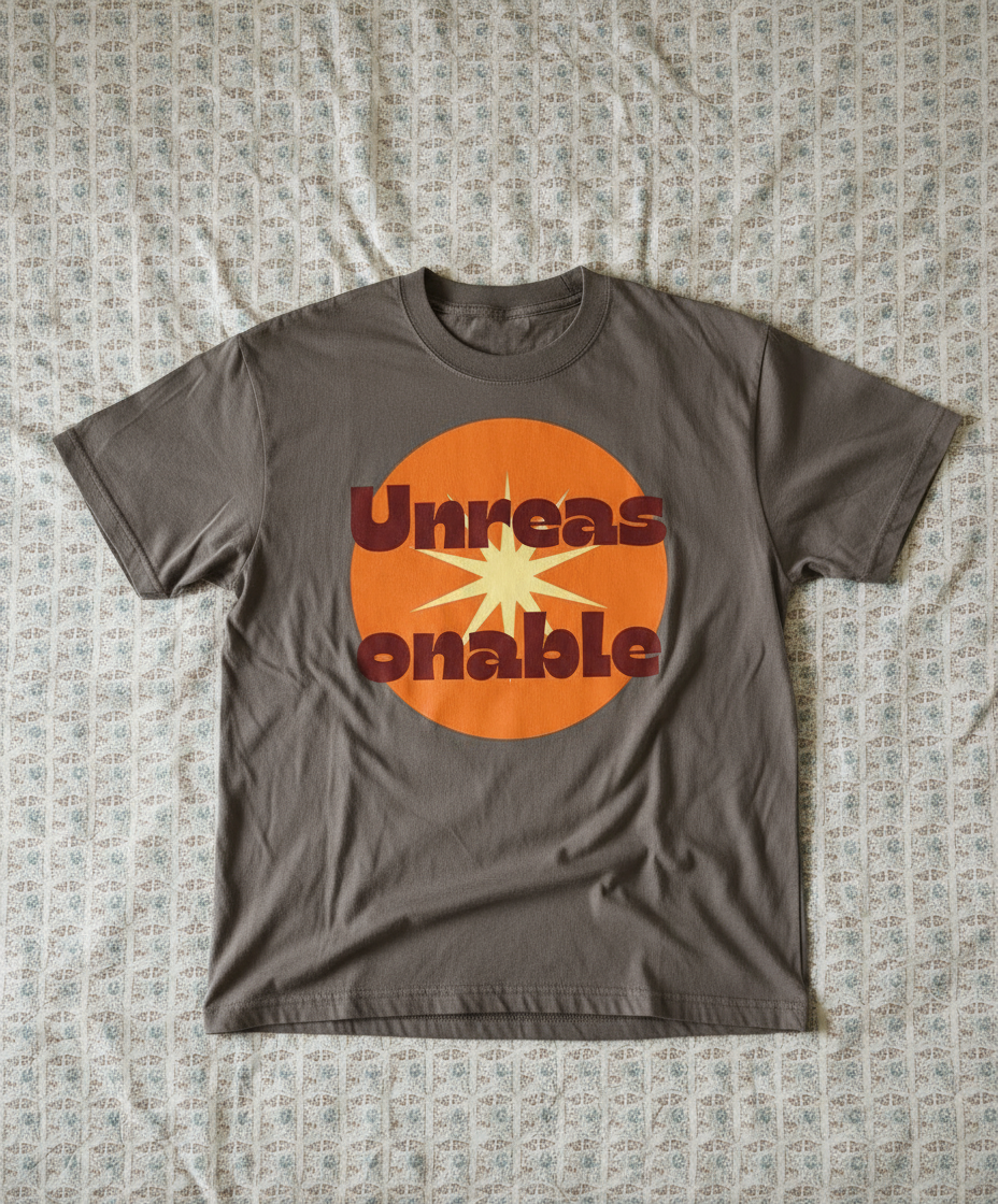 Grey t-shirt with an orange and red graphic design on a textured surface