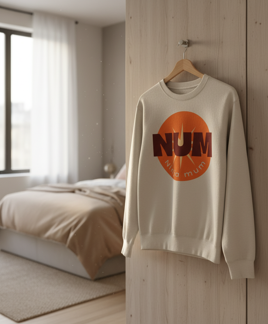 Beige sweatshirt with orange logo hanging on a wooden door in a bedroom.